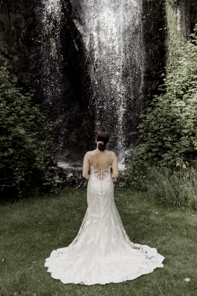 bride poses in front of waterfall at this Olympic View Golf Club wedding