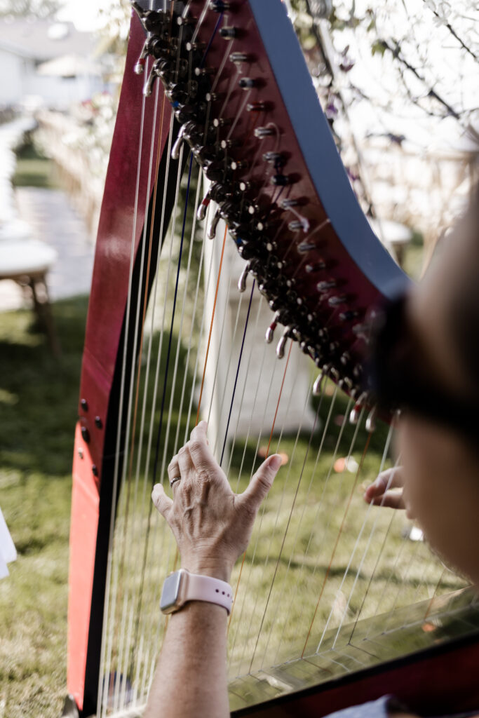 An up close of a harpist playing a song at the ceremony at this lakeside wedding at Alberta Beach