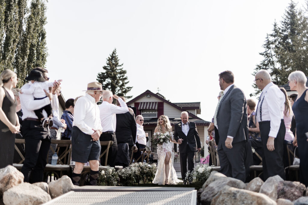 the bride's father walks her down the aisle at this lakeside wedding at Alberta Beach