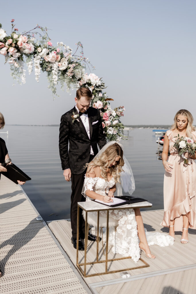 The bride signs the wedding papers at this lakeside wedding at Alberta Beach