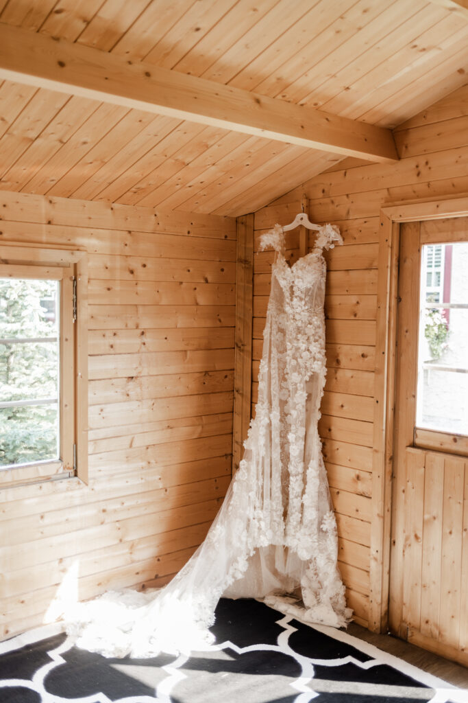 The wedding dress hanging in a wood cabin at this lakeside wedding at Alberta Beach