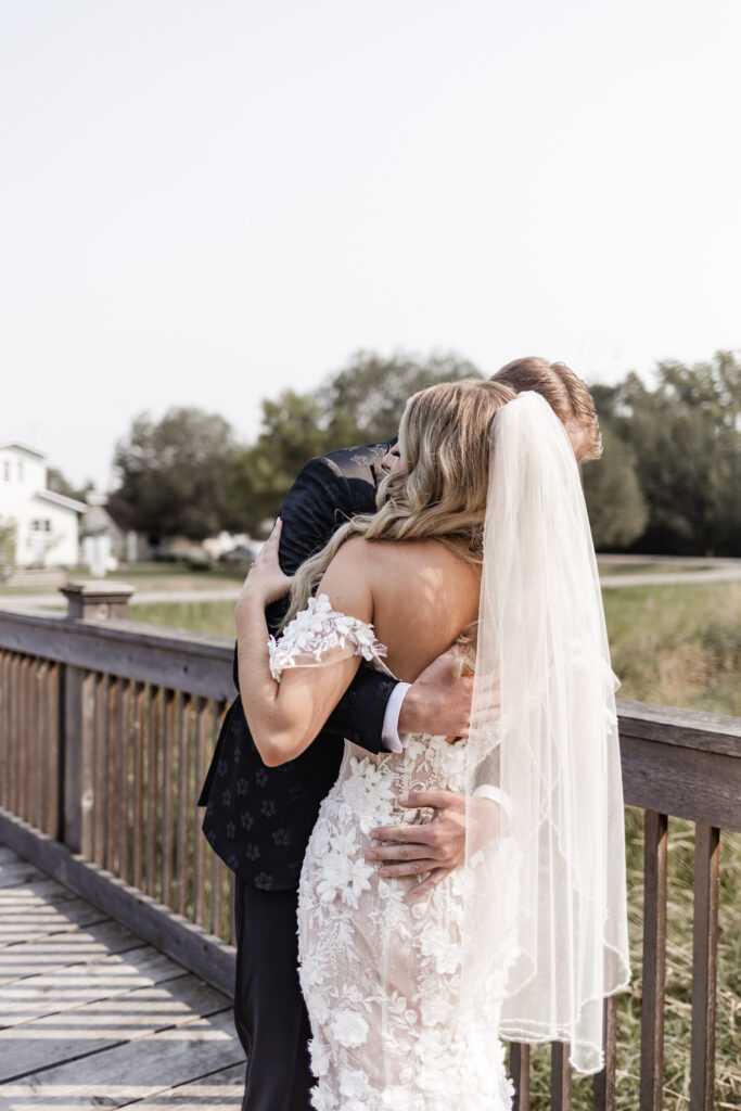 Bride and groom hug during their first look at this lakeside wedding at Alberta Beach