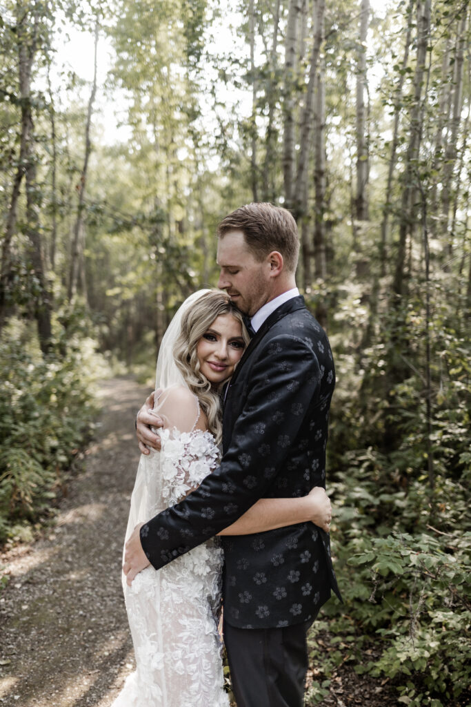 Bride and groom embrace in a forest at this lakeside wedding at Alberta Beach