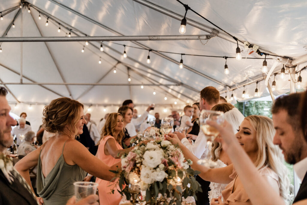 The guest cheers their drinks at this lakeside wedding at Alberta Beach