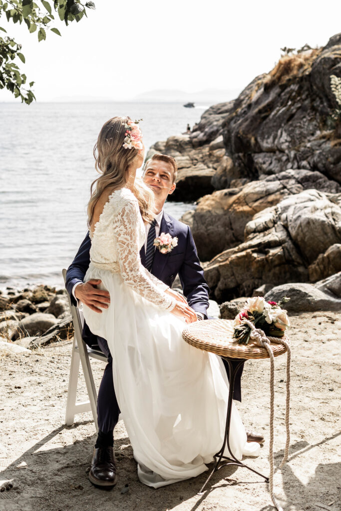 Bride sits on grooms lap to sign the wedding papers at this Whytecliff Park elopement