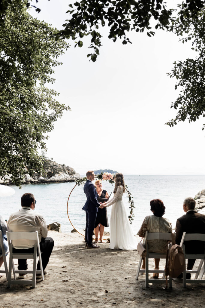 Bride and groom hold hands at the altar in front of the ocean view at their Whytecliff Park elopement