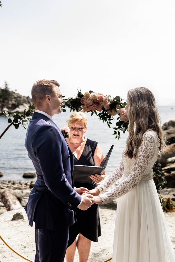 Bride and groom hold hands and smile at each other at the altar at this Whytecliff Park elopement