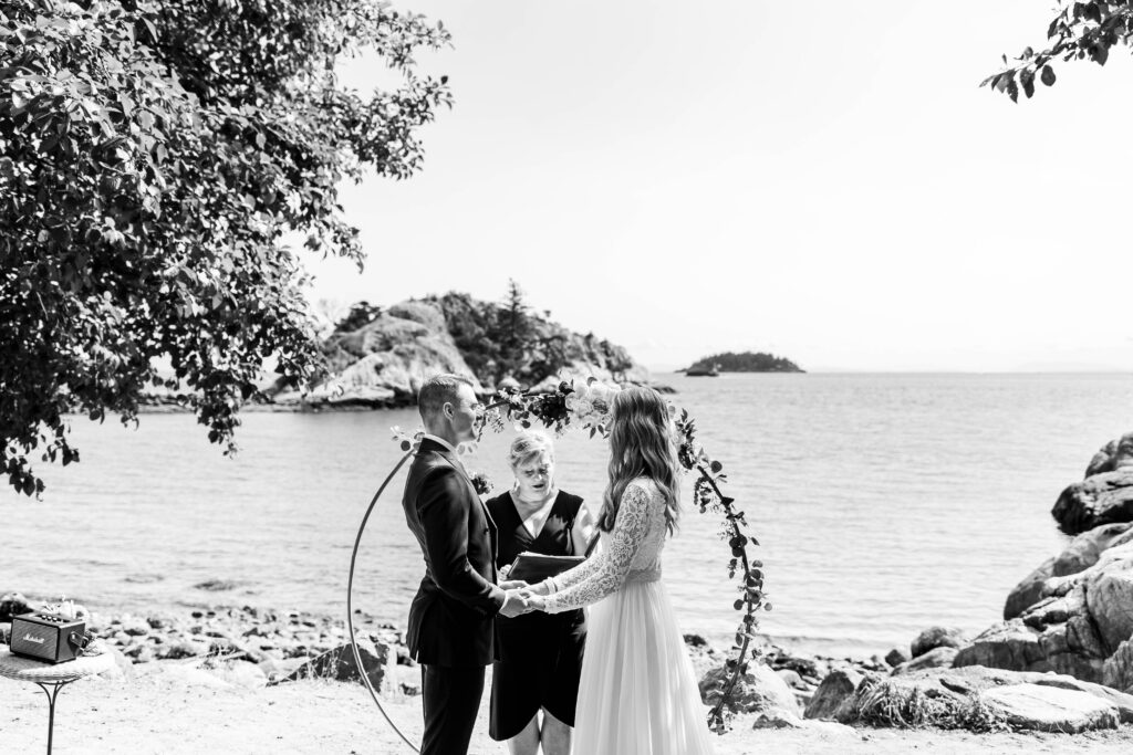 Bride and groom hold hands at the altar overlooking an ocean view at this Whytecliff Park elopement