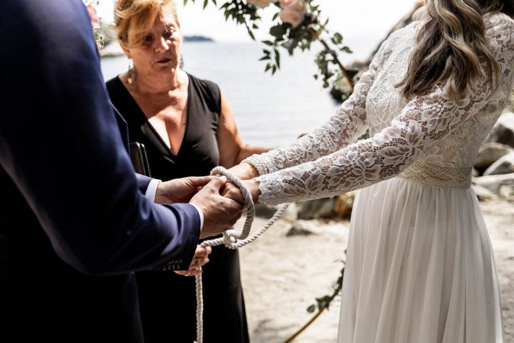 An upclose of the couples hands tied together during their hand fasting ceremony at this Whytecliff Park elopement