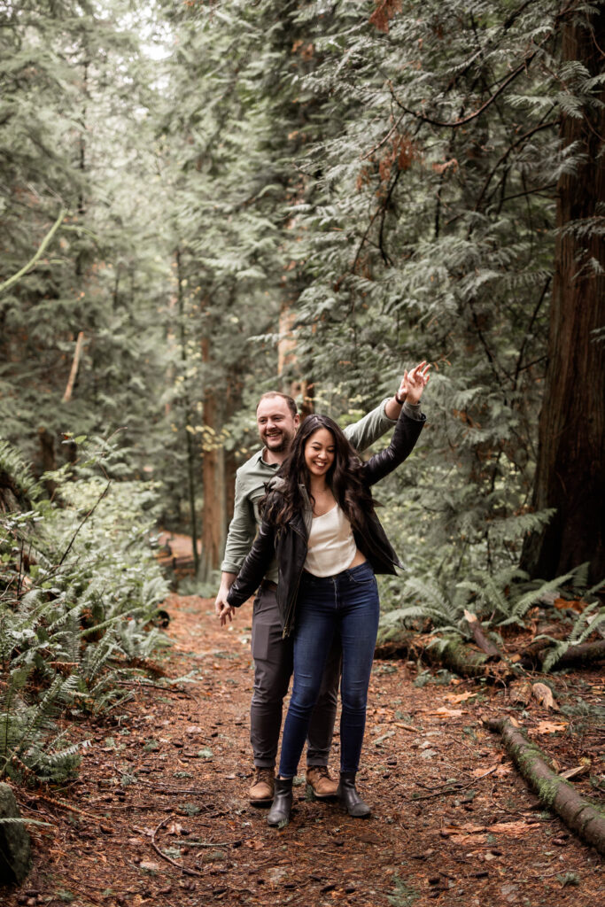 Couple posing naturally on a secluded path at Lighthouse Park for their engagement session.