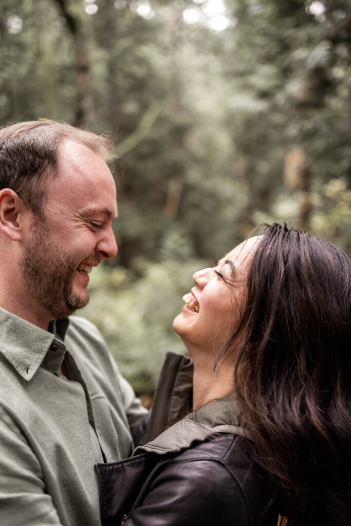 A couple’s laughter captured in an authentic moment during their Lighthouse Park engagement session.