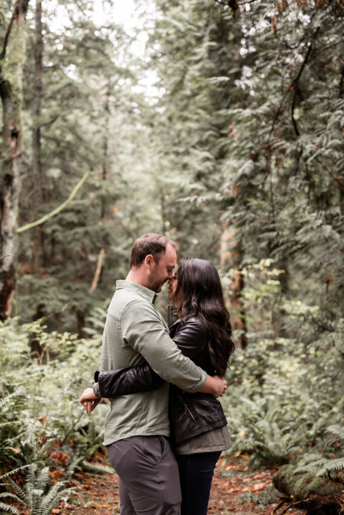 Engaged couple framed by lush greenery during a photoshoot at Lighthouse Park.