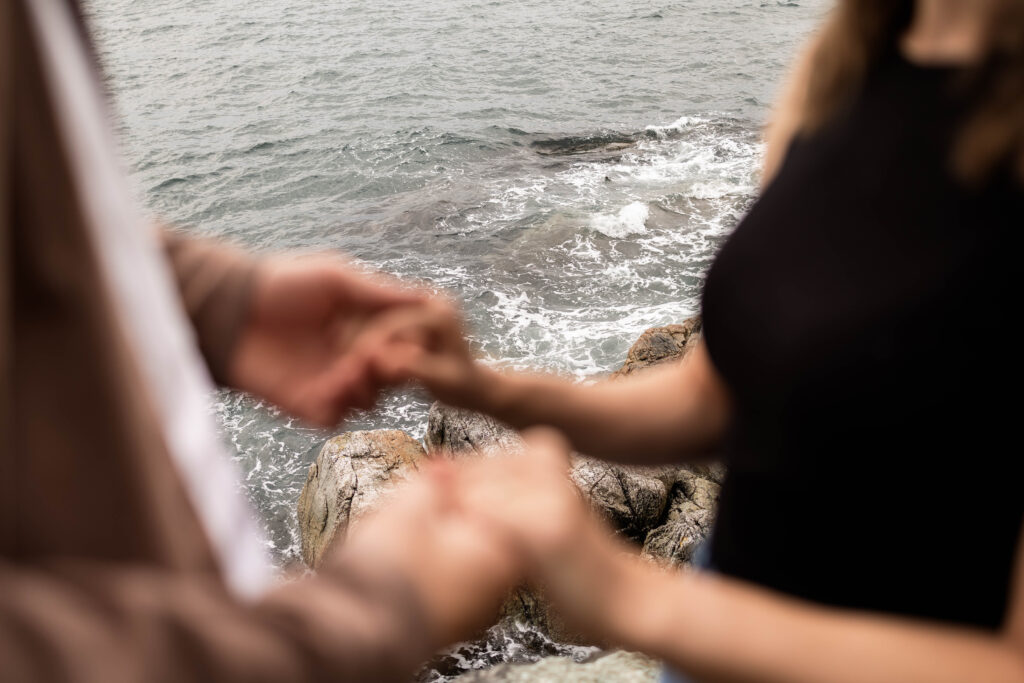 Ben and Stef holding hands with the ocean in the background at their Lighthouse Park Engagement Shoot