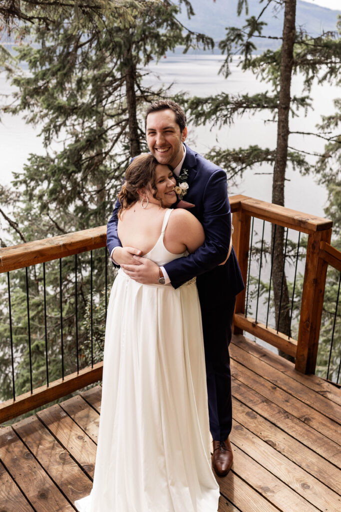 Bride and groom share a hug overlooking Mabel Lake at their elopement