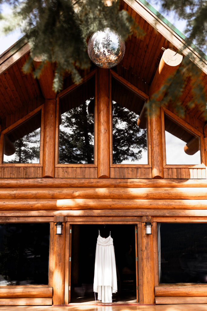 The bride's wedding dress hanging up in the doorway of the cabin at this Mabel Lake elopement