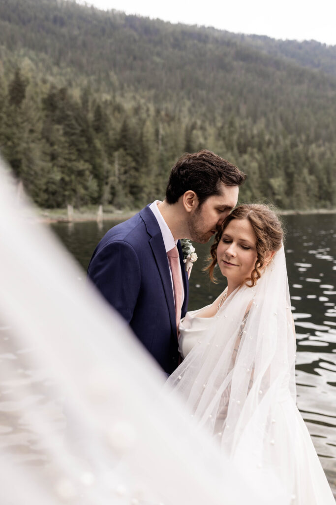 Bride and groom framed by a sweeping veil at this Mabel Lake elopement