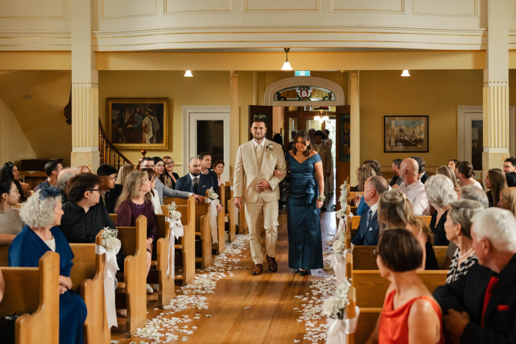 Groom walking down the aisle with his mother at his Victoria cathedral wedding