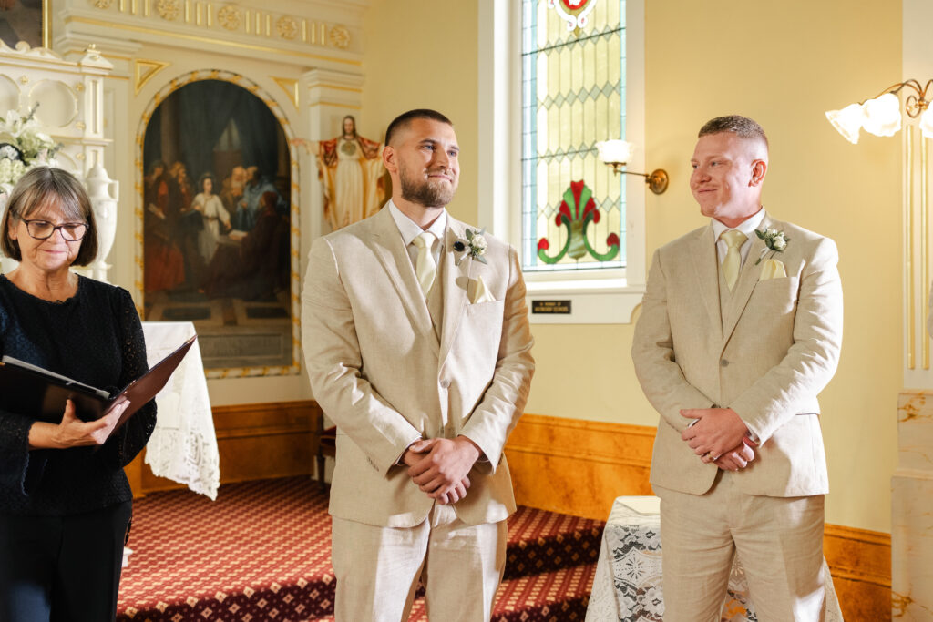 Groom smiling white waiting for bride to walk down the aisle at his Victoria cathedral wedding