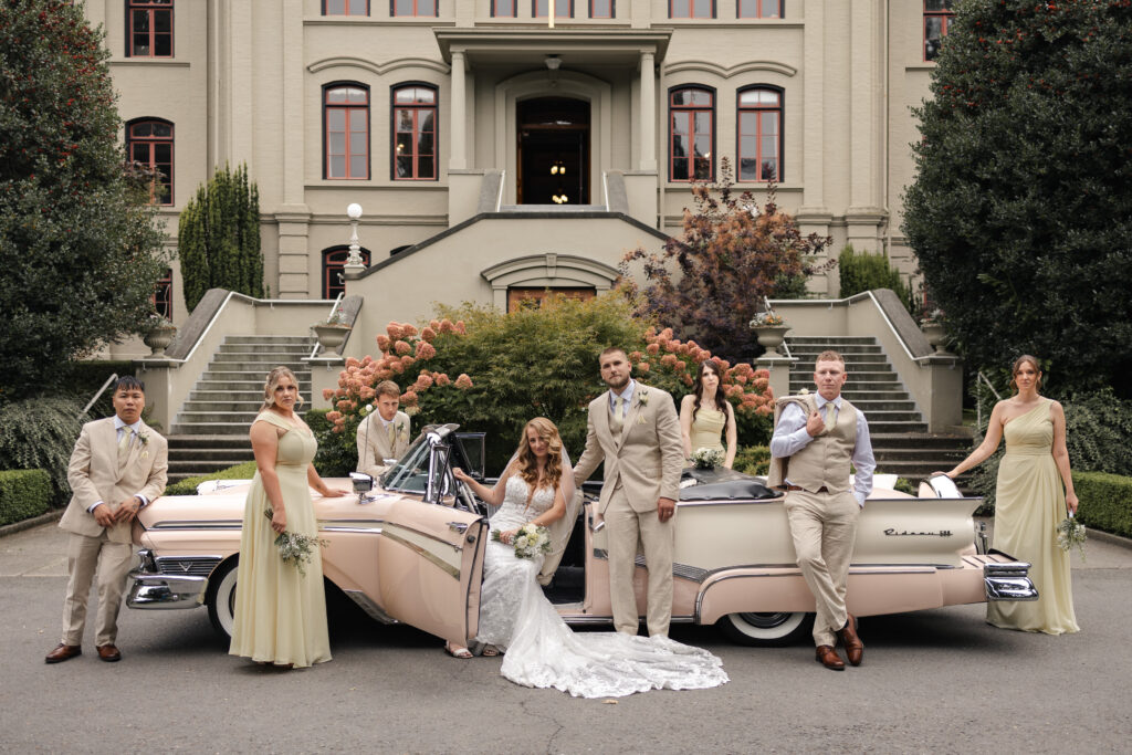Bridal party poses around a pink vintage car outside of St. Ann's Academy at this Victoria cathedral wedding