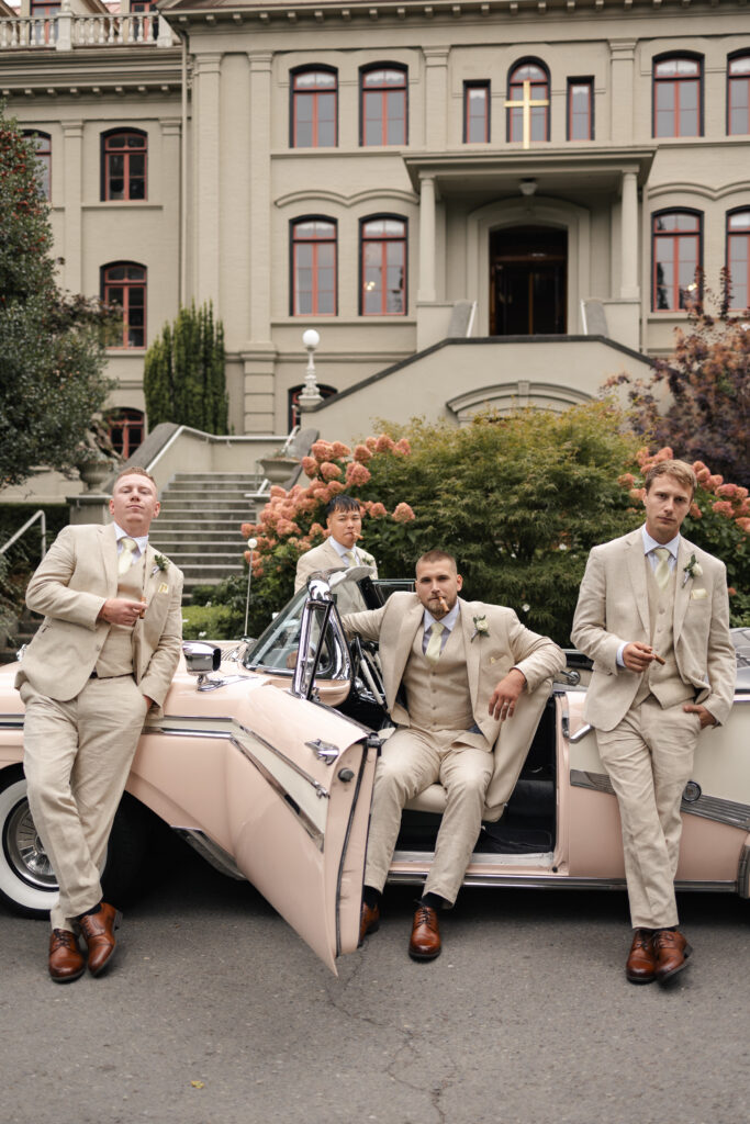 Groomsmen pose dramatically in front of pink vintage car at this Victoria cathedral wedding
