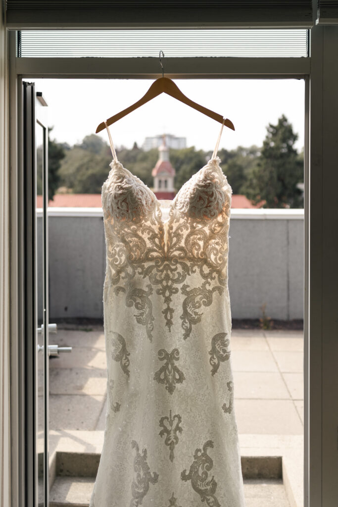 Wedding dress hanging in hotel room of Parkside Hotel, with view of St. Ann's Cathedral in the back